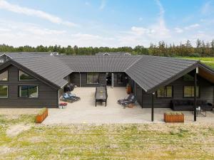 a house with a black roof and a patio at 20 person holiday home in Nørre Nebel in Nørre Nebel