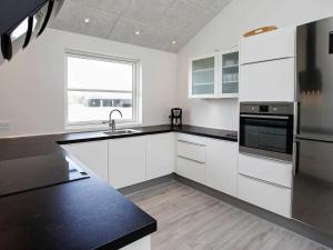 cocina con armarios blancos y encimera negra en 10 person holiday home in L kken, en Løkken
