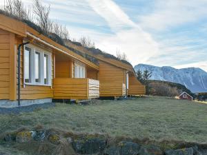 une maison en bois avec des montagnes en arrière-plan dans l'établissement Holiday home Aukra, à Aukra