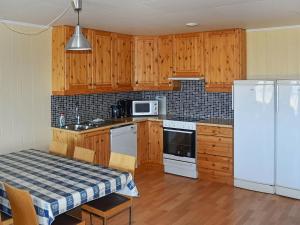 cocina con armarios de madera y nevera blanca en Holiday home Aukra IV, en Aukra
