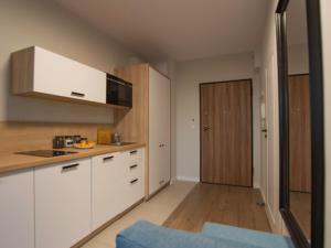 eine Küche mit weißen Schränken und Holzböden in der Unterkunft Morze-kwatery Apartament z HUŚTAWKĄ Bel Mare in Misdroy