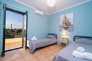 a bedroom with two beds and a balcony at Sea View Antigone's Villa with playground in Metaxáta