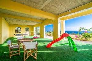 a play room with a table and chairs and a slide at Sea View Antigone's Villa with playground in Metaxáta