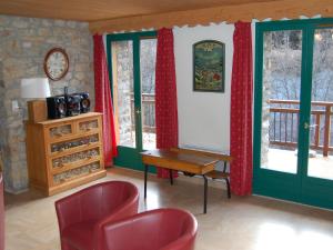 Le VillardにあるMagnificent chalet with saunaの赤いカーテンとテーブルが備わる客室で、一部の客室には窓が付いています。