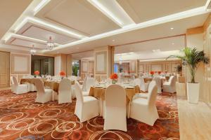 a banquet hall with tables and white chairs at Lemon Tree Premier, Delhi Airport in New Delhi