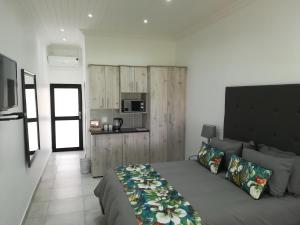 a bedroom with a large bed and a kitchen at The Gamtoos Ferry Hotel in Jeffreys Bay