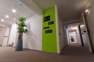 a green wall in a hallway with a plant at Hotel Sonia Self Check In Only in Trieste