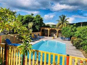 a swimming pool with chairs and a fence at Residence Deshroses in Deshaies