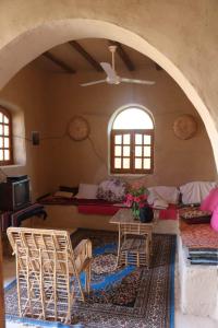 Desert Rose Guesthouse في الأقصر: غرفة معيشة مع طاولة وكراسي في غرفة
