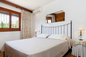 ein weißes Schlafzimmer mit einem großen Bett und einem Spiegel in der Unterkunft Sa Rota in Santa Eulària des Riu