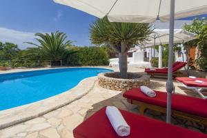 - une piscine avec 2 chaises rouges et un parasol dans l'établissement Pau de Baix, à Sant Antoni de Portmany