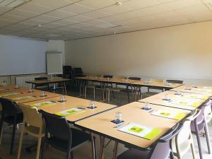 a classroom with rows of tables and chairs at Logis Hôtel-Restaurant Les Loges in Chantepie