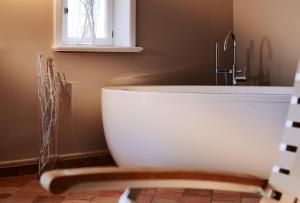 a bath tub in a bathroom with a sink at SalzWasserHerz Senhoog Luxury Holiday Homes ***** in Morsum