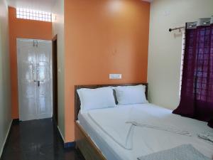a bed in a room with an orange wall at Vijayanagara Home Stay in Hampi