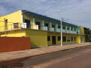 a yellow building with a balcony on a street at Pousada Potiguara Irapuan in Iranduba
