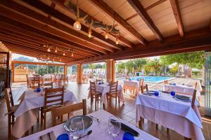 ein Restaurant mit weißen Tischen und Stühlen sowie einem Pool in der Unterkunft Agroturismo Es Quatre Cantons in Binissalem