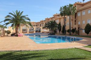 une piscine avec des palmiers devant un immeuble dans l'établissement 187 Palm Beach - Deniasol, à Dénia