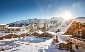 a resort in the snow with the sun shining at Alpin Chalets Oberjoch - Luxus Unterkunft mit privatem SPA und Zugang zu 3000 qm SPA Panoramahotel Oberjoch in Bad Hindelang