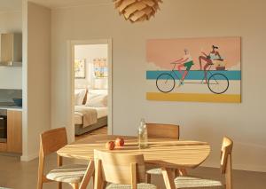 a dining room with a table and a painting of two women riding a bike at Eol Apartments Split Žnjan Beach in Split