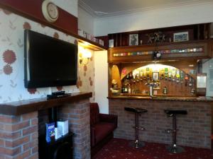 a bar with a television and a fireplace at Strides Hotel in Blackpool