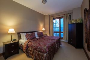 a bedroom with a large bed and a window at L'Équinoxe Rendez-Vous Mont-Tremblant in Mont-Tremblant