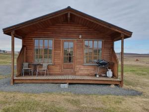 Guesthouse Stöng and Cottages في Stöng: كابينة خشبية مع طاولة وكراسي في حقل