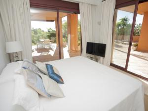 ein weißes Bett mit Kissen und ein TV im Schlafzimmer in der Unterkunft GRAN BAHIA de Marbella in Marbella