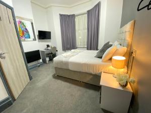 a bedroom with a bed and a desk and a television at Park City Rooms in Manchester