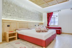 Un dormitorio con una cama y un sofá rojo. en Cesa San Florian - Appartamento 1, en Canazei