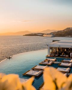 un complejo con piscina y océano al atardecer en Cavo Tagoo Mykonos, en Mykonos ciudad