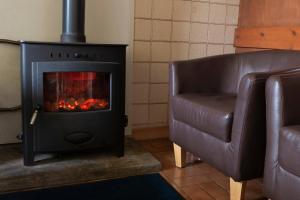 a living room with a fireplace and a leather chair at Durness Youth Hostel in Durness