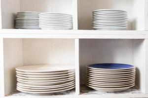 two shelves filled with white plates in a kitchen at Durness Youth Hostel in Durness