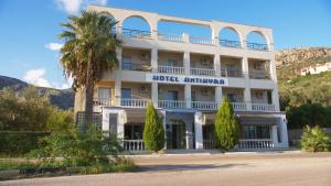 a hotel with a palm tree in front of a building at Antikyra Beach Hotel in Antikyra
