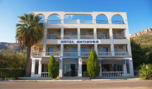 Antikyra Beach Hotel في أنتيكيرا: فندق فيه نخلة امام مبنى