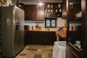a kitchen with wooden cabinets and a stainless steel refrigerator at Eudora Full Guest House in Tsagarada