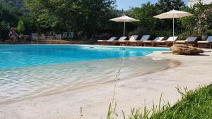 a swimming pool with chairs and umbrellas and a beach at Terre e Torri Country Resort in Lascari