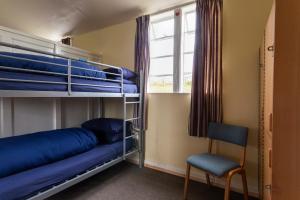 een slaapkamer met een stapelbed, een stoel en een raam bij Durness Youth Hostel in Durness