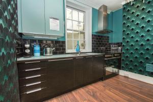 a kitchen with black cabinets and blue walls and a window at Chocolate Box - Central- by Brighton Holiday Lets in Brighton & Hove