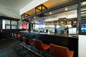 un bar avec une rangée de tabourets de bar dans l'établissement Bastion Hotel Zoetermeer, à Zoetermeer