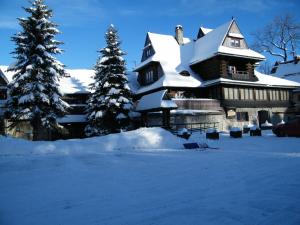 una casa ricoperta di neve con due alberi di Natale di Pensjonat Jastrzębia Turnia a Zakopane