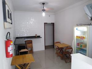 a kitchen with a refrigerator and a table and chairs at Pousada Vitória in Aparecida