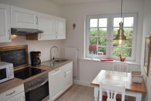 a kitchen with white cabinets and a sink and a table at Ferienwohnung-Clarissa in Morsum