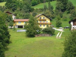 ein gelbes Haus auf einem Hügel mit einem grünen Feld in der Unterkunft Landgut Feuersang in Sankt Veit im Pongau