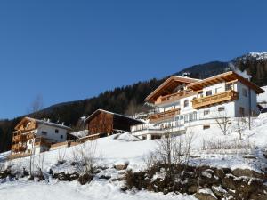 a building on a snow covered hill with trees at Appartements Sonngarten in Campo Tures