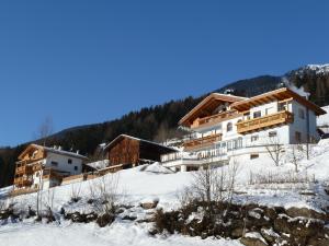 un edificio en una colina cubierta de nieve con árboles en Appartements Sonngarten en Campo Tures