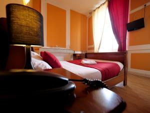 um quarto com uma cama, uma secretária e uma janela em L'Alzire - Auberge Culturelle em Jarnages