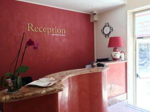 a red wall with a reception counter in a room at Albergo Perseo in Portopalo