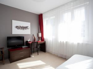 um quarto com uma cama e uma secretária com uma televisão em Residhotel Lille Vauban em Lille