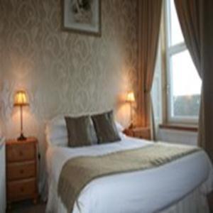 a bedroom with a bed with two lamps and a window at Royal Hotel in Girvan