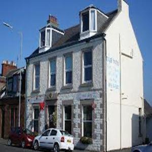 a white building with a car parked in front of it at Royal Hotel in Girvan